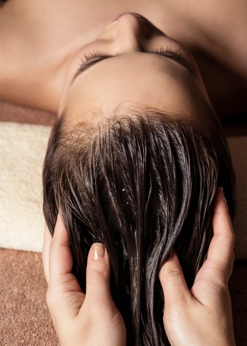 cosmetologist massaging hair on the head of the woman spa treat